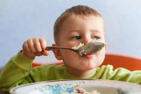 Hungry child eats lunch with big appetite. Cute boy eats pasta. Stock Photos