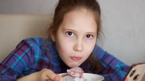A hungry child quickly eats porridge for breakfast. Funny little girl Video stock 263010938
