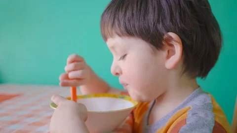 Hungry four year old boy eating porridge from bowl at home Stock Footage 73038575