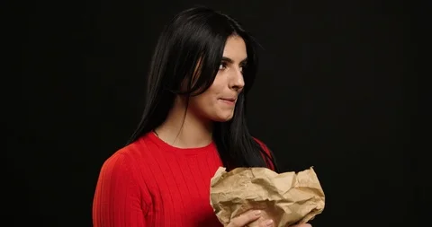 Hungry girl eats a croissant until no one sees it. Isolated over black 스톡 동영상 120608664