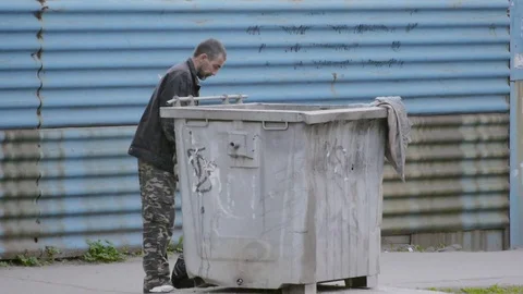 Hungry homeless man looking in garbage container Stock Footage 75306252