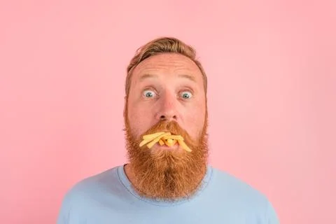 Hungry man with beard and tattoos eats fried potatoes Stock Photos