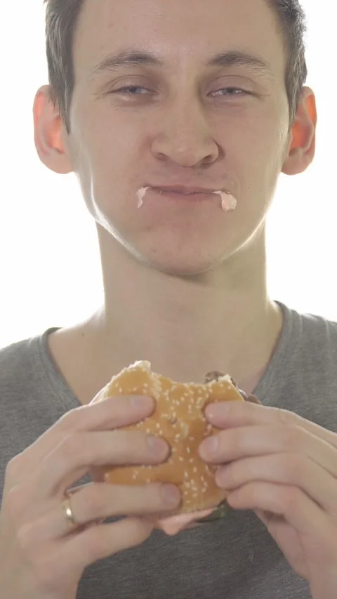 Hungry man eating a messy beef burger with enjoyment and sauce dripping from his Stock Footage 341580051