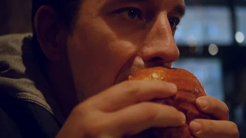 A hungry man eats a hamburger in a cafe, bites a large piece. HD, 1920x1080 Stock Footage 103674196
