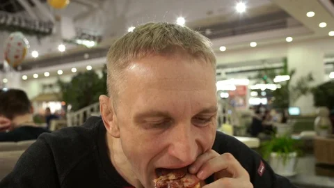 A hungry man greedily eats pizza, sits in a shopping center Stock Footage 88921720