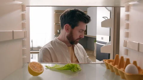 Hungry man guy open empty refrigerator with half lemon lettuce leaf one egg Stock Footage 245830828