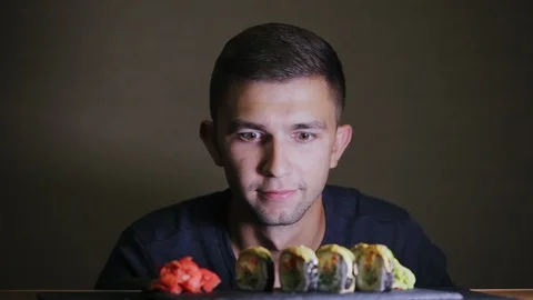 A hungry man looks at sushi, does not eat, waits, considers rolls Stock Footage 97349593