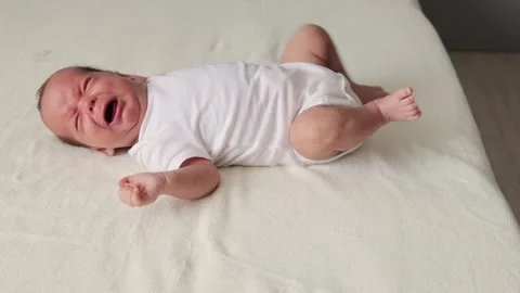 Hungry sad baby crying on bed on white sheet being sick or hungry needs to Stock Footage 291310954