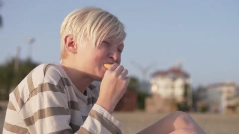 A hungry schoolboy eats a croissant on a city beach, Turkey, Alanya Stock Footage 234643745