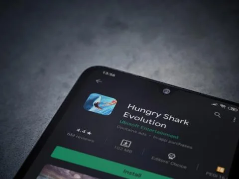 Hungry Shark Evolution app play store page on the display of a black mobile s Stock Photos