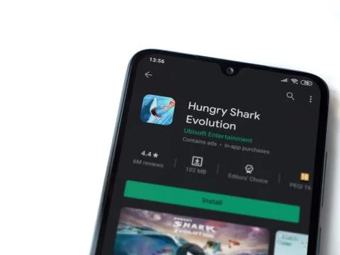 Hungry Shark Evolution app play store page on the display of a black mobile s Stock Photos