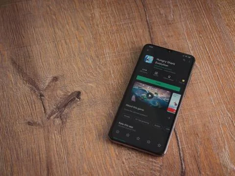 Hungry Shark Evolution app play store page on the display of a black mobile s Stock Photos