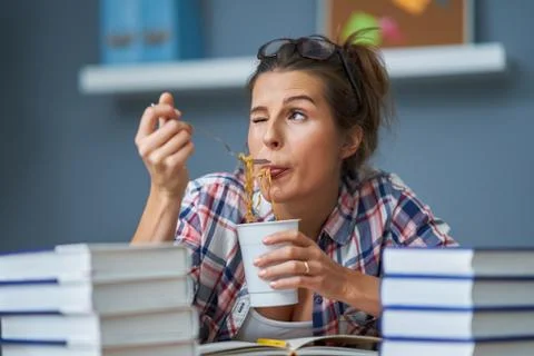 Hungry student eating noodle while learning at home Stock Photos