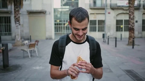 Hungry student eats sandwich on his way Stock Footage 81393174