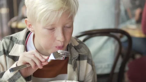 A hungry teenage boy eats breakfast in a restaurant Stock Footage 224714495
