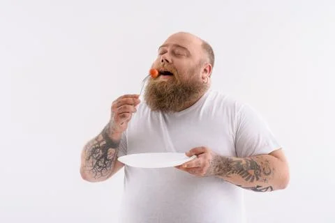 Hungry thick guy eating tiny vegetable Stock Photos