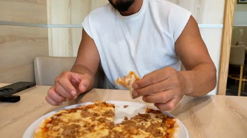 Hungry Young Athletic Man Biting into Hot Slice of Fresh Baked Tuna Pizza a.. Video stock 347199984