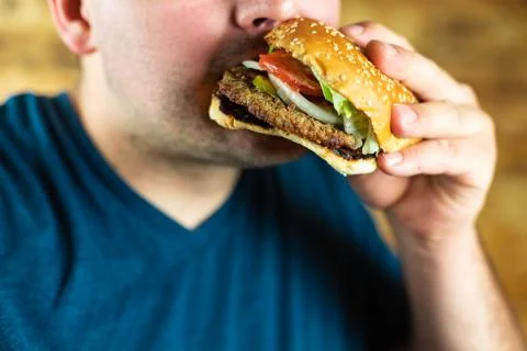 The hungry young man aggressively eats a burger. Fast food Stock Photos