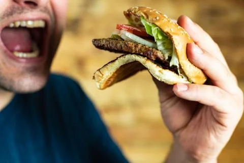 The hungry young man aggressively eats a burger. Fast food Stock Photos