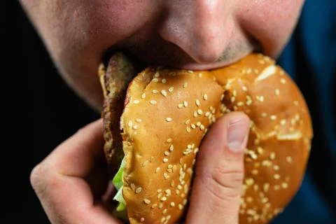 The hungry young man aggressively eats a burger. Fast food Stock Photos