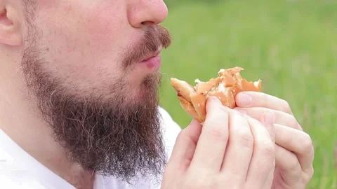 Hungry young man eats a delicious burger Stock Footage 241783185