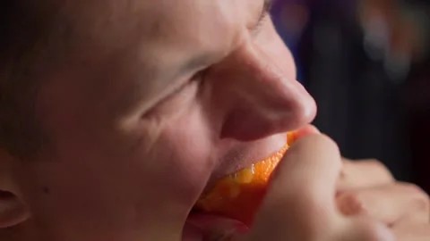 Hungry young man greedily eats orange Stock Footage 150126084