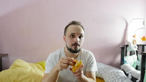 Hungry young man making grimaces and eating a piece of pizza at home. Stock Footage 124931964
