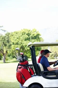 On the hunt for a missing ball. two men in a cart driving across a golf course. Stock Photos