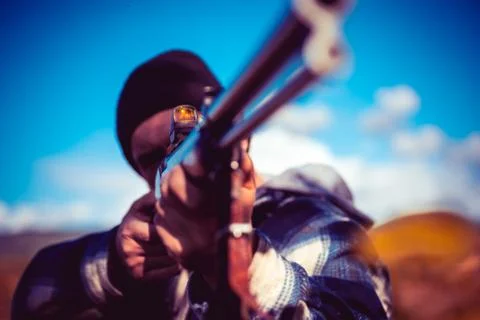 Hunter aiming rifle in forest. Hunter with shotgun gun on hunt. Autumn hunting Stock Photos