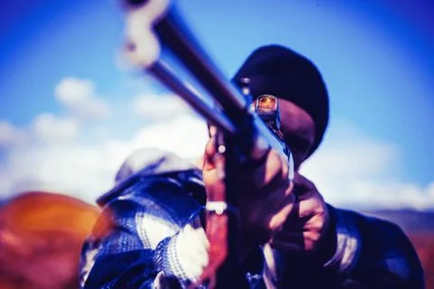 Hunter aiming rifle in forest. Hunter with shotgun gun on hunt. Autumn hunting Stock Photos
