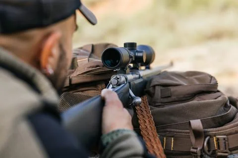 Hunter aiming with rifle scope in wilderness setting Stock Photos