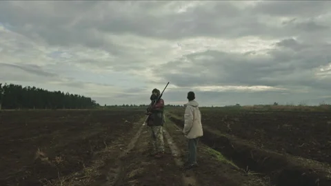 Hunter and his son walking on a muddy road Stock Footage 330565165