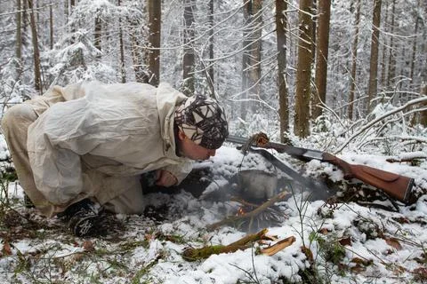 Hunter blows the fire in the winter forest Stock Photos