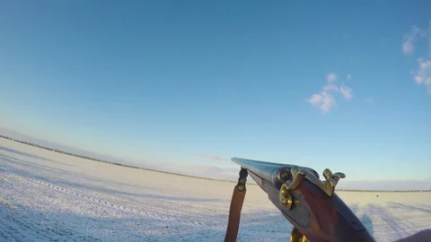 Hunter carries a gun in front of him in the winter field Vídeos de archivo 83472001