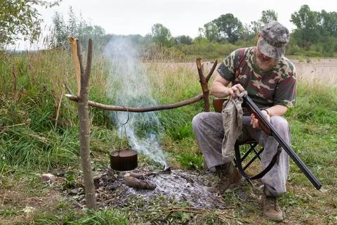 Hunter cleans weapons in a field camp Stock Photos