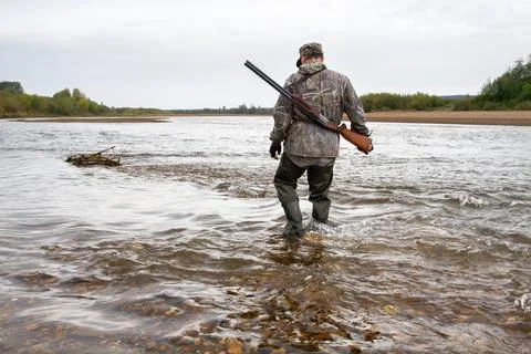 The hunter crosses the river Stock Photos