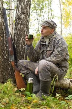 A hunter drinks tea while resting on a fallen tree Stock Photos