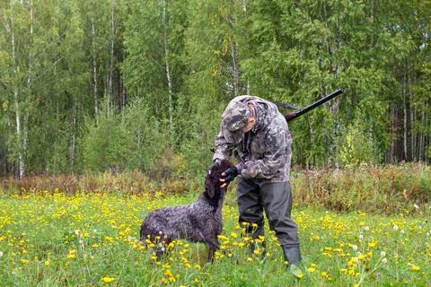 The hunter examines the muzzle of the dog Stock Photos