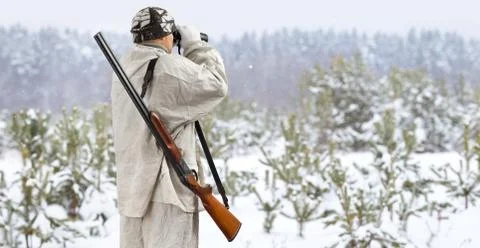 The hunter examines the winter forest through binoculars Stock Photos