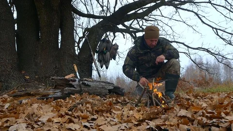 Hunter in the forest makes a fire at a rest time Stock Footage 100631319