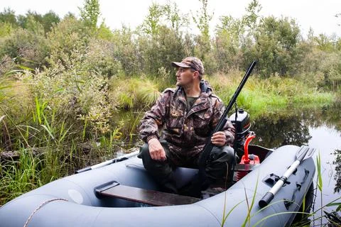 Hunter with a gun in the boat Stock Photos