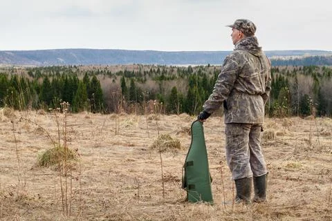 A hunter with a gun case is standing in a clearing Stock Photos