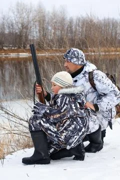 Hunter with his son on the riverside Stock Photos