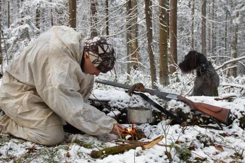 The hunter lights a fire in winter Stock Photos