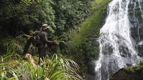 Hunter looking at waterfall in the jungle. Stock Footage 50031692