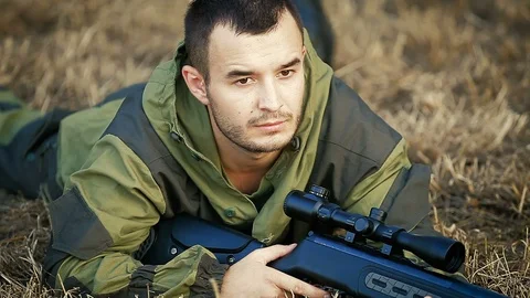 Hunter is lying in a field and prepare to shoot Видео 89777799