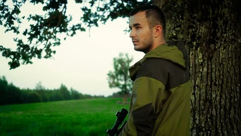 Hunter is lying in a field and prepare to shoot Видео 89778229