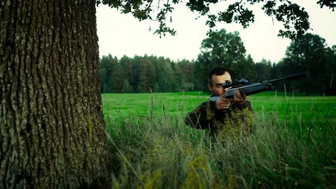 Hunter is lying in a field and prepare to shoot Stock Footage 89778716