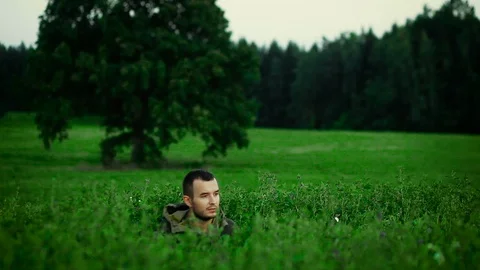 Hunter is lying in a field and prepare to shoot Stockbeeldmateriaal 89779124