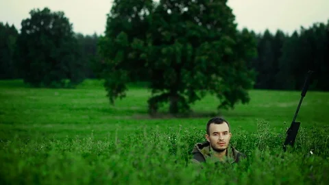 Hunter is lying in a field and prepare to shoot Vídeos de archivo 90345488